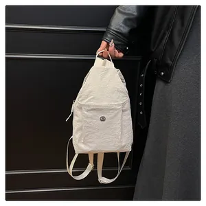 Close-up of white nylon backpack with wrinkled texture and round metal logo detail