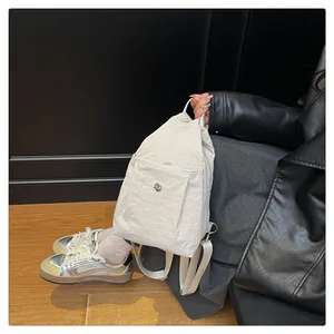 Detail of a creamy white nylon backpack with pleated texture and round metal buckle