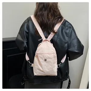 Pink nylon backpack detail on a model wearing black jacket for stylish contrast