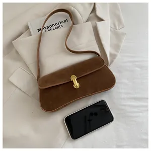 Gros plan d'un sac baguette en daim marron avec boucle dorée et échelle smartphone