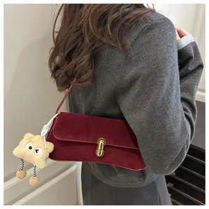 Détail du sac sous le bras en daim bordeaux avec fermoir doré et pendentif étoile en peluche