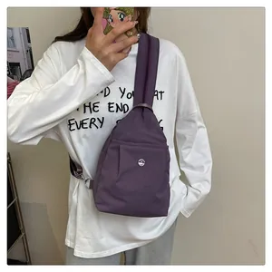 Detail view of purple nylon chest bag with metallic M logo and pleated front pocket texture