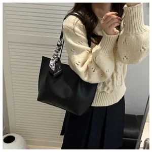 Detail of black faux leather tote bag with stylish marble pattern scarf on the handle