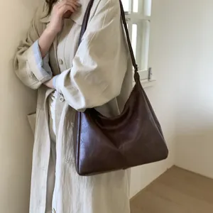 Retro large coffee brown PU leather tote bag worn with a beige trench coat for women