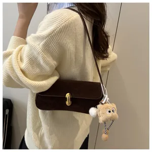 Détail du sac à bandoulière en daim marron foncé avec fermoir doré et charme peluche