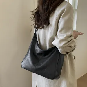 Minimalist black soft leather tote bag for women showing a stylish shoulder carry pose