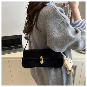 Détail du sac sous l'aisselle en daim noir avec boucle dorée et breloque ours en peluche