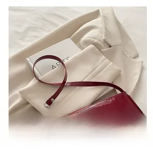 Detail of red patent leather baguette bag with high-gloss finish and adjustable shoulder strap