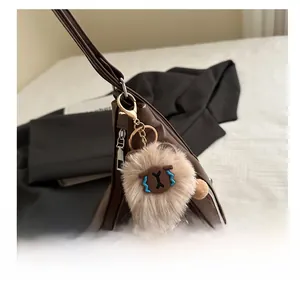 Close-up of a plush bear charm with blue details on a brown leather tote bag side