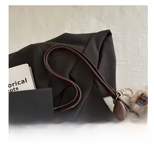 Detail of dark brown leather tote bag strap and side zipper with cute sheep plush pendant