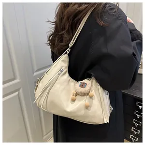 Detail of soft beige leather hobo bag with fringe zipper and cute plush bear charm