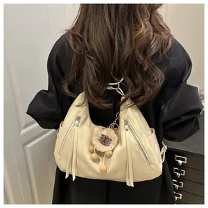 Detail of cream-white half-moon tote bag with zippers and plush sheep charm decoration