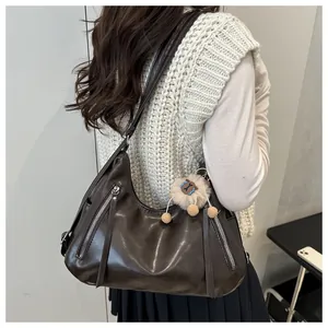 Detailed side view of dark brown faux leather hobo bag with zip accents and plush charm
