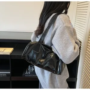 Dettaglio borsa a spalla in pelle nera lucida con pieghe naturali e design minimale