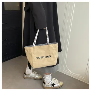 Detail of khaki canvas tote bag featuring woven rope handles and side storage pocket