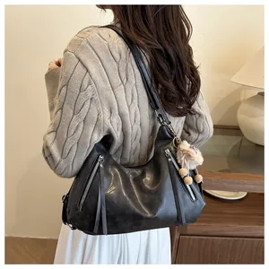 Close-up of black soft leather tote bag with stylish metal zippers and long tassel details