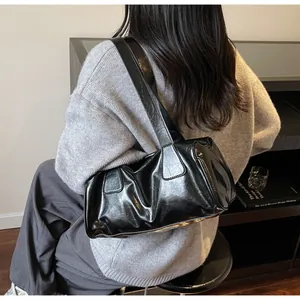 Dettaglio della borsa a spalla nera lucida con effetto stropicciato e tracolla