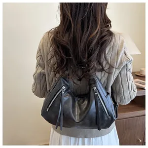 Detail of a soft black PU leather hobo bag with unique diagonal zippers for women