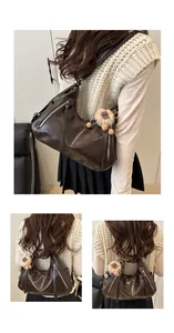 Detail of coffee brown soft leather hobo bag with metal zippers and plush charm