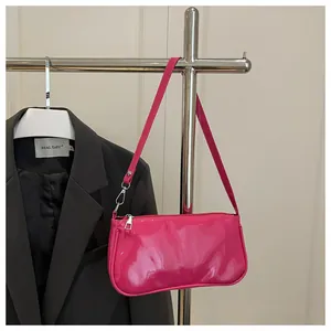 Close-up of glossy magenta patent leather baguette bag with silver zipper detail