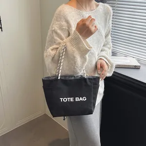 Minimalist black canvas tote bag with TOTE BAG print and spiral handles for daily use