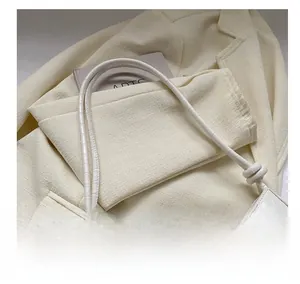 Detail of creamy white faux crocodile texture handbag featuring a knotted shoulder strap