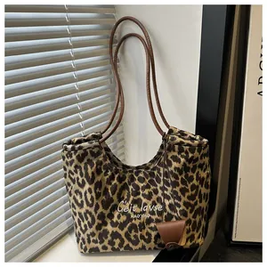 Close-up of leopard print suede tote bag with brown leather handles in soft window light
