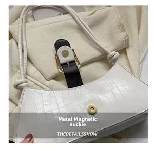 Detail of the golden metal magnetic clasp on a white faux leather crocodile handbag