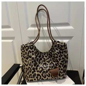 Detail of leopard print tote bag with brown leather strap and small triangle charm