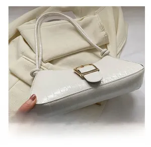 Detail view of the flat bottom structure and crocodile texture of the white baguette bag