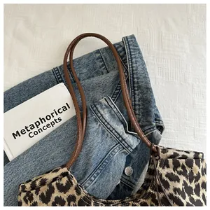Detail of leopard print faux suede tote bag with slim brown shoulder straps on fabric