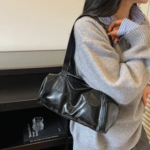 Borsa a spalla retrò nera lucida a pieghe stile Boston indossata da una modella elegante