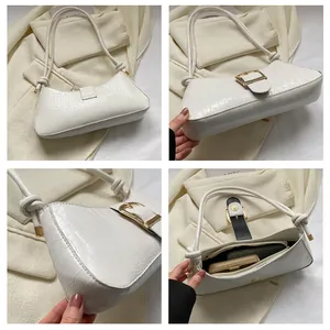 Detail of white crocodile embossed underarm bag with gold buckle and internal storage capacity