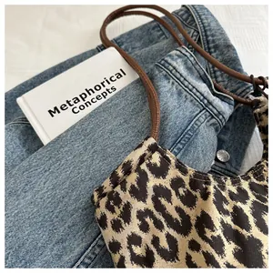 Top view of leopard print tote bag on denim fabric with a minimalist book prop
