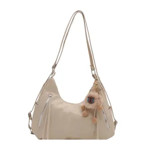 Minimalist beige soft leather hobo bag with zipper tassels and plush charm detail