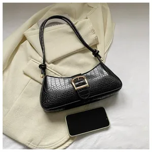 Close-up of black crocodile pattern baguette bag with golden buckle on beige suit