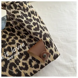 Detail of leopard print suede tote with white embroidery and leather triangle tag