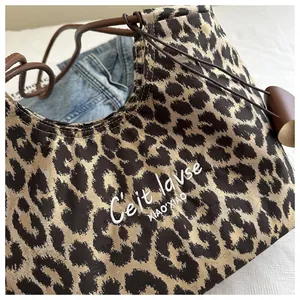 Detail shot of leopard print hobo bag featuring white embroidery and leather drawstring strap
