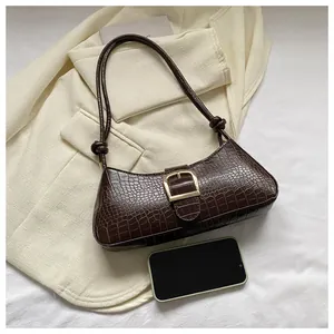 Detail of dark brown faux crocodile baguette bag with gold horseshoe buckle and knot strap