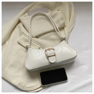 Detail of white crocodile embossed baguette bag with elegant gold metal buckle closure