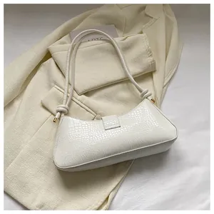 Detailed view of white crocodile pattern baguette bag with stylish knot detail on strap