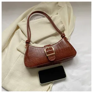 Brown crocodile-textured baguette bag with gold buckle and a knotted shoulder strap