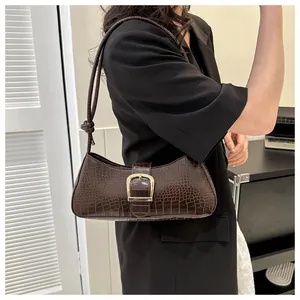 Detail of a dark coffee crocodile pattern underarm bag with a gold metal buckle detail