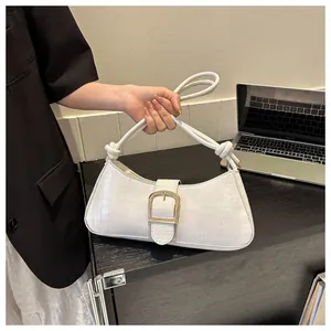 Close-up of white crocodile pattern baguette bag with gold buckle and knot strap detail