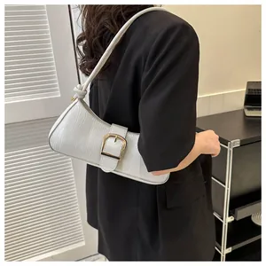 Close-up of white crocodile pattern baguette bag with a large golden metal buckle strap