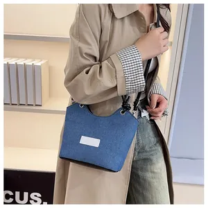 Sac bandoulière chic en denim bleu avec coutures contrastées et bandoulière noire nouée