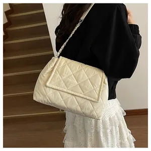 Detailed view of cream quilted chain bag worn by a model on a shoulder for daily style
