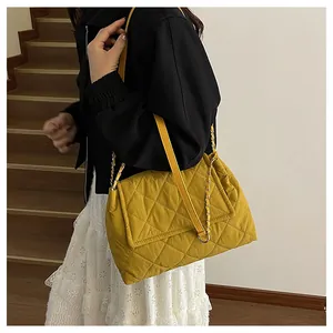 Detail of yellow quilted chain shoulder bag featuring elegant embroidery stitching