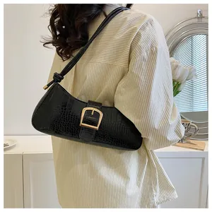 Detail view of black crocodile pattern baguette bag with a striking gold buckle clasp