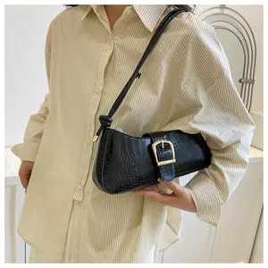 Close-up of black crocodile embossed shoulder bag with golden horseshoe buckle detail